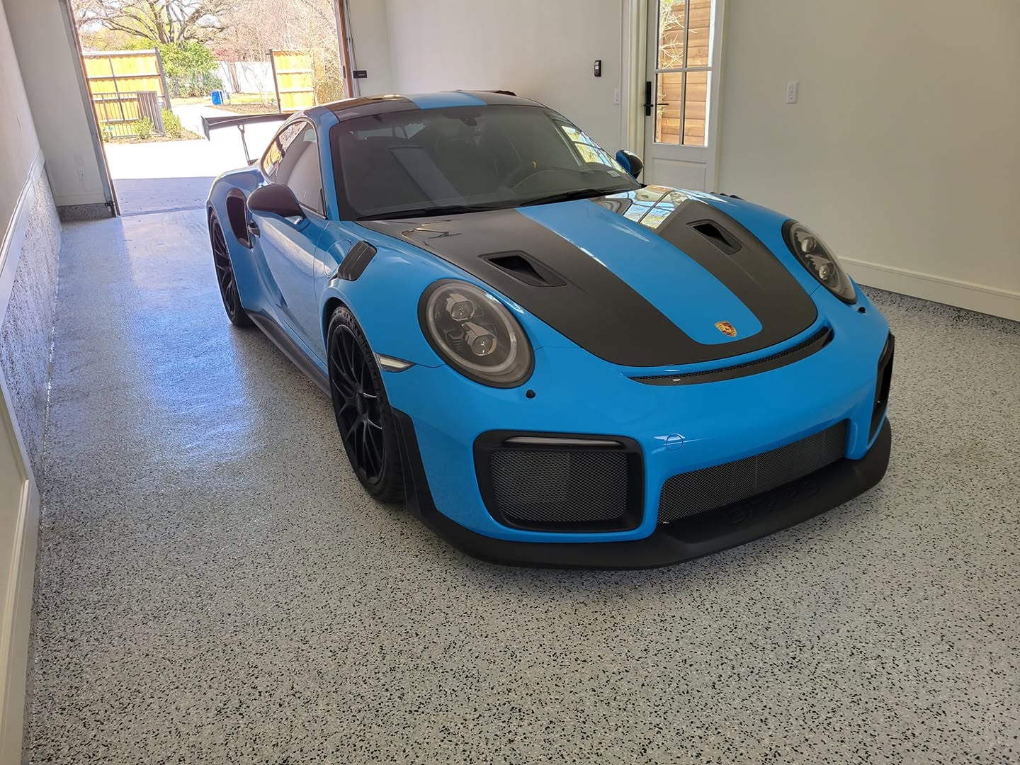 Speckled flake epoxy garage floor under a blue Porsche 911